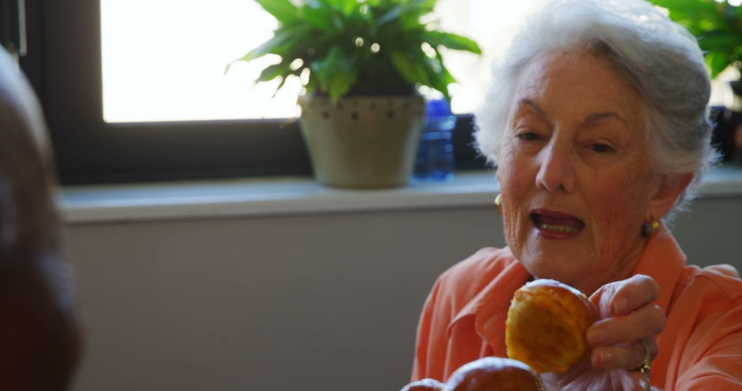 Senior Woman Offering Homemade Pastries Indoors - Free Images, Stock Photos and Pictures on Pikwizard.com