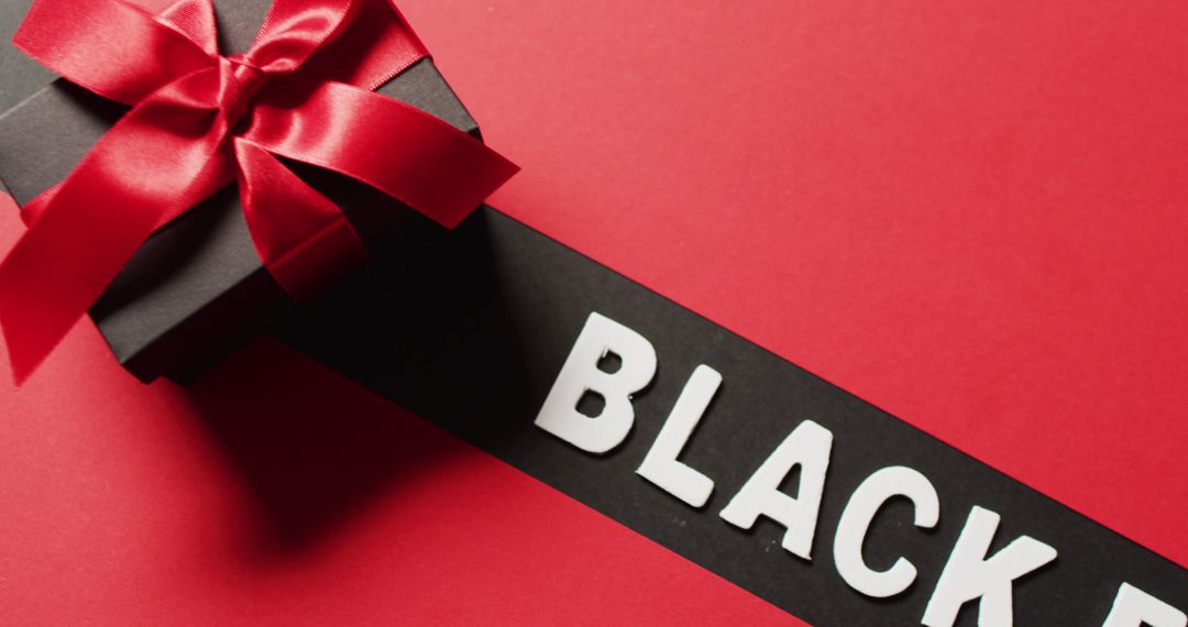 Black friday text in white on black stripe and black gift box with red ribbon, on red background - Free Images, Stock Photos and Pictures on Pikwizard.com