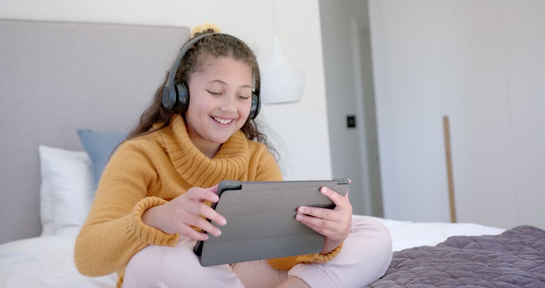 Cheerful Young Girl Enjoying Tablet with Headphones in Cozy Bedroom - Free Images, Stock Photos and Pictures on Pikwizard.com