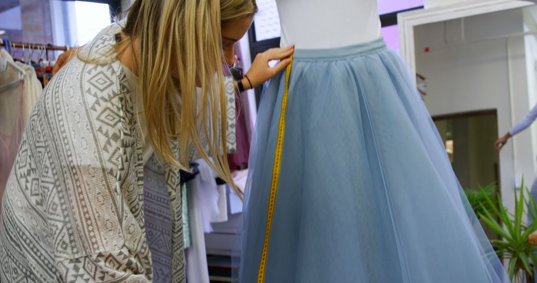A meticulous fashion designer measures a garment on a mannequin, ensuring precision. - Free Images, Stock Photos and Pictures on Pikwizard.com
