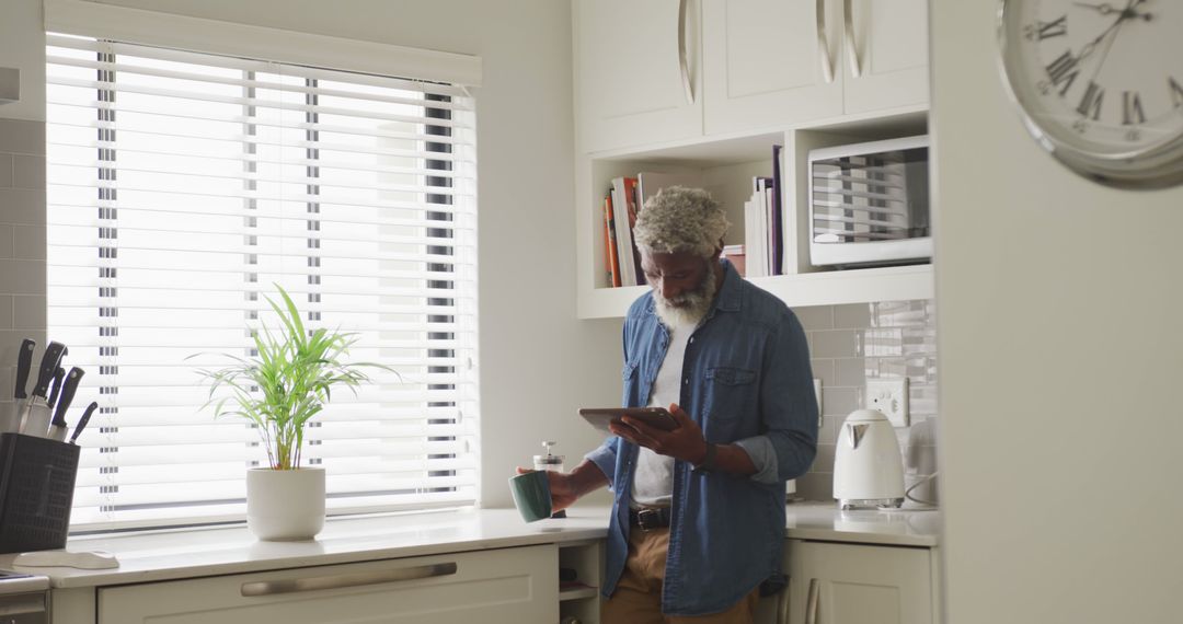 Retired Man Enjoying Coffee and Digital Tablet in Modern Kitchen - Free Images, Stock Photos and Pictures on Pikwizard.com