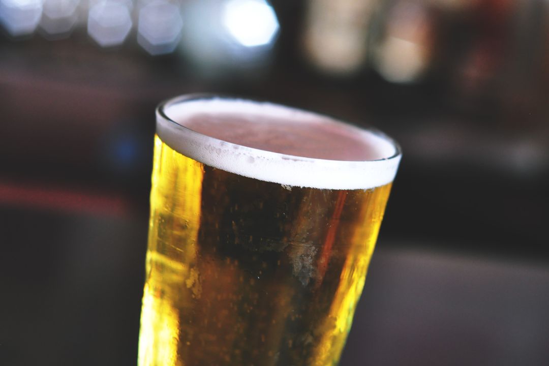 Glowing Golden Draft Beer Pint with Frothy Head and Soft Bokeh Bar Background