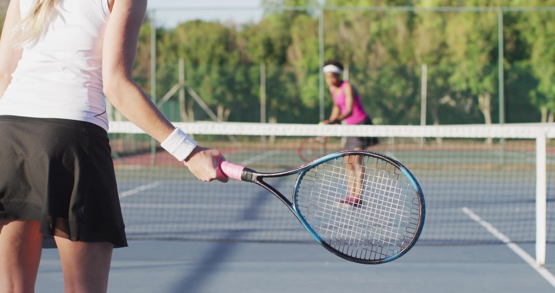 Female tennis player swinging racket on blue court with opponent at net, dynamic match