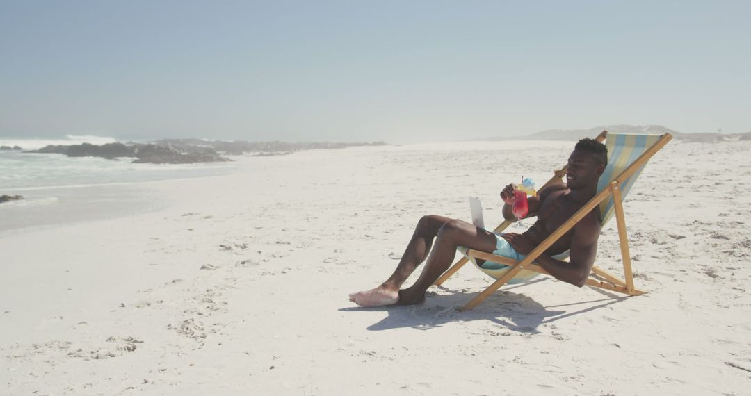 Young Man Relaxing on Beach With Tropical Drink - Free Images, Stock Photos and Pictures on Pikwizard.com