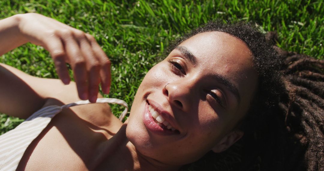 Smiling Woman Lying on Grass in Sunlight - Free Images, Stock Photos and Pictures on Pikwizard.com