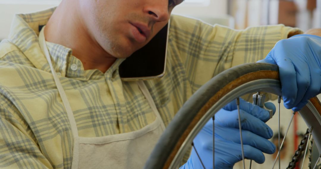 Mechanic Fixing Bicycle Tire While Talking on Mobile Phone - Free Images, Stock Photos and Pictures on Pikwizard.com