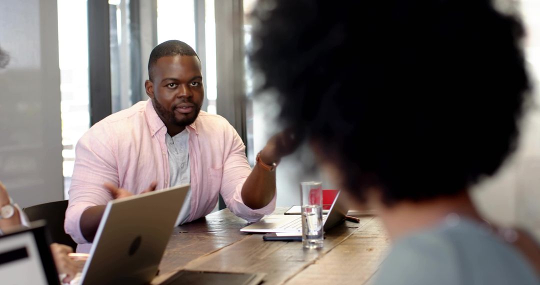 Executive presenting strategy and leading team meeting in modern boardroom with laptops