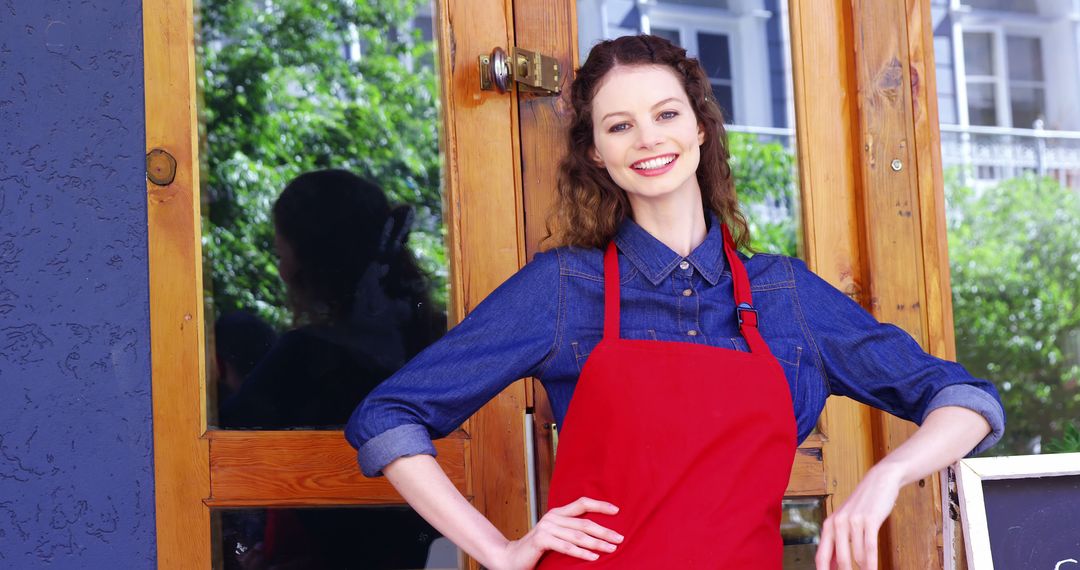 Smiling Female Barista Standing Outside Cafe in Red Apron - Free Images, Stock Photos and Pictures on Pikwizard.com