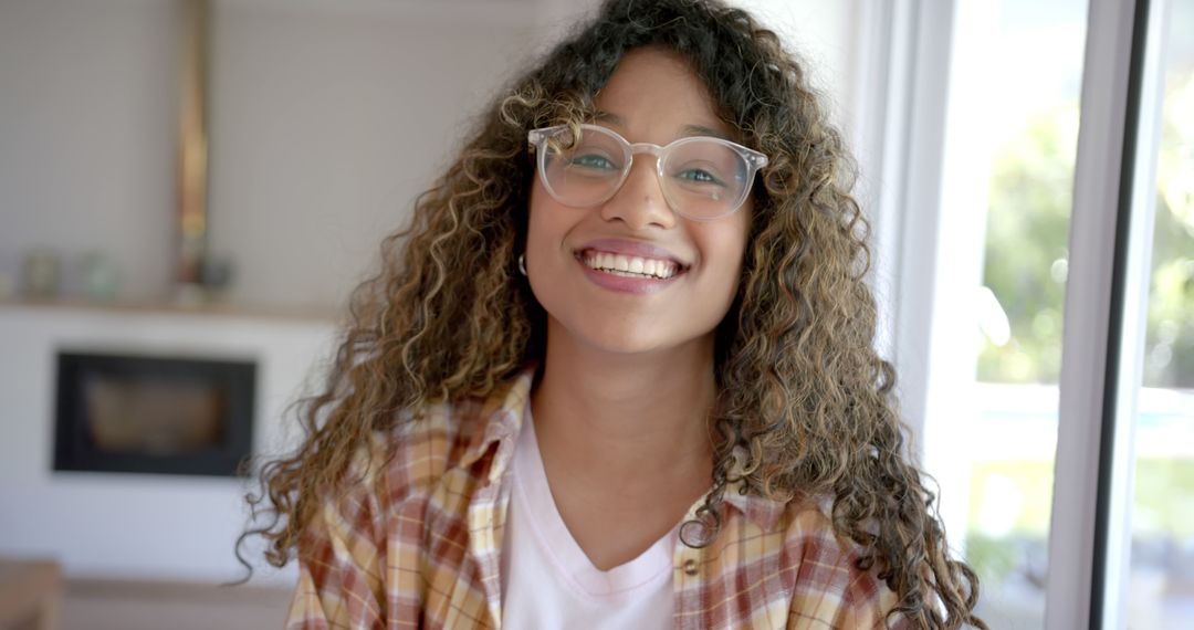 Smiling Teen Girl with Curly Hair and Glasses in Casual Shirt Indoors - Free Images, Stock Photos and Pictures on Pikwizard.com