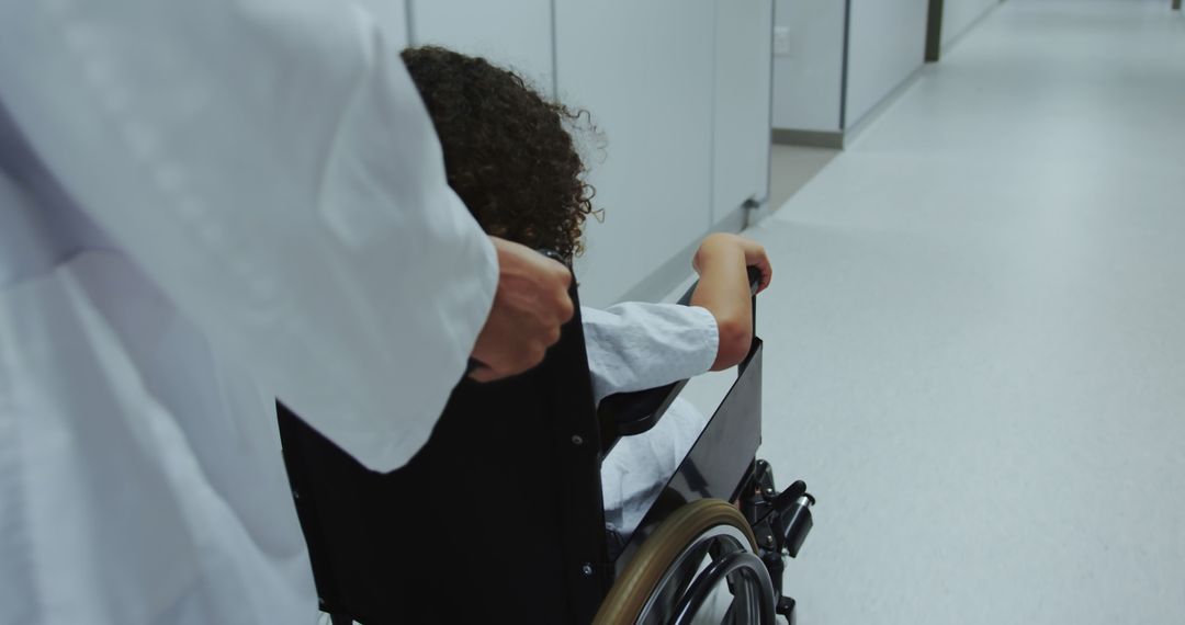 Doctor Assisting Child in Wheelchair through Hospital Corridor - Free Images, Stock Photos and Pictures on Pikwizard.com