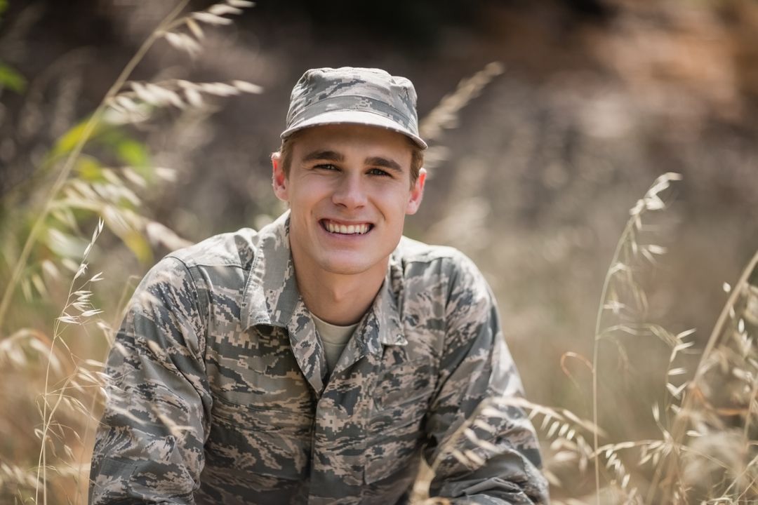 Portrait of happy military soldier crouching in grass - Free Images, Stock Photos and Pictures on Pikwizard.com