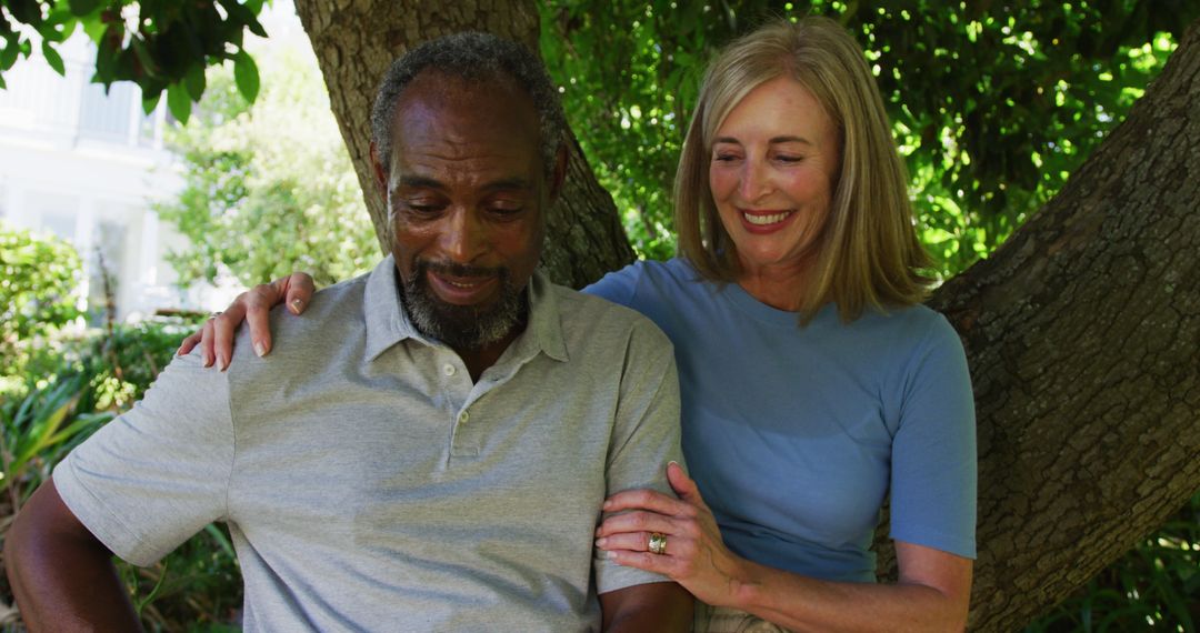 Diverse senior couple in garden taking selfie sitting under a tree and smiling - Free Images, Stock Photos and Pictures on Pikwizard.com