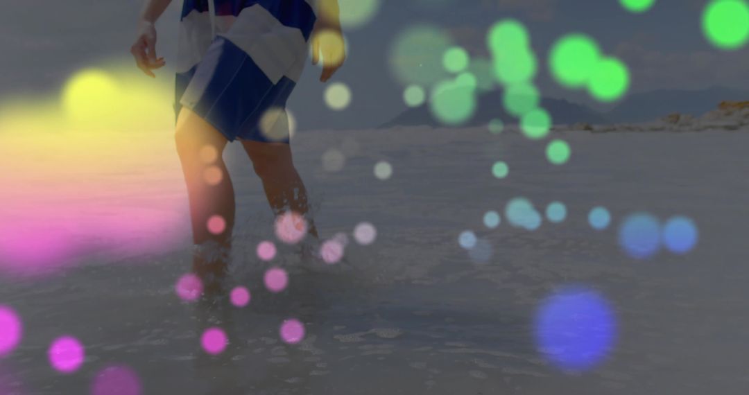 Person Walking Through Shallow Coastal Waters with Colorful Bokeh Effect