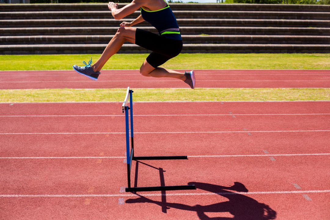 Female Athlete Jumping Over Hurdle on Track - Free Images, Stock Photos and Pictures on Pikwizard.com