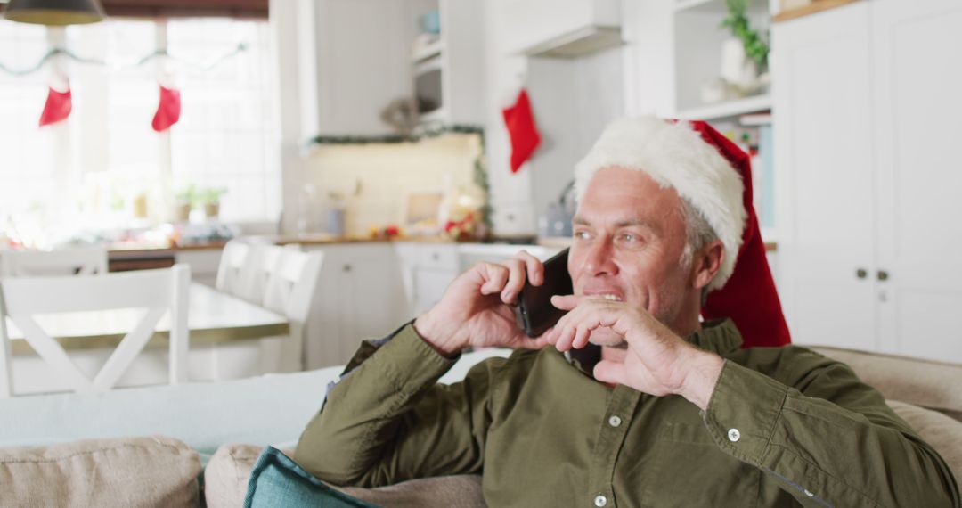 Middle-aged Man in Santa Hat Talking on Phone in Festively Decorated Kitchen - Free Images, Stock Photos and Pictures on Pikwizard.com