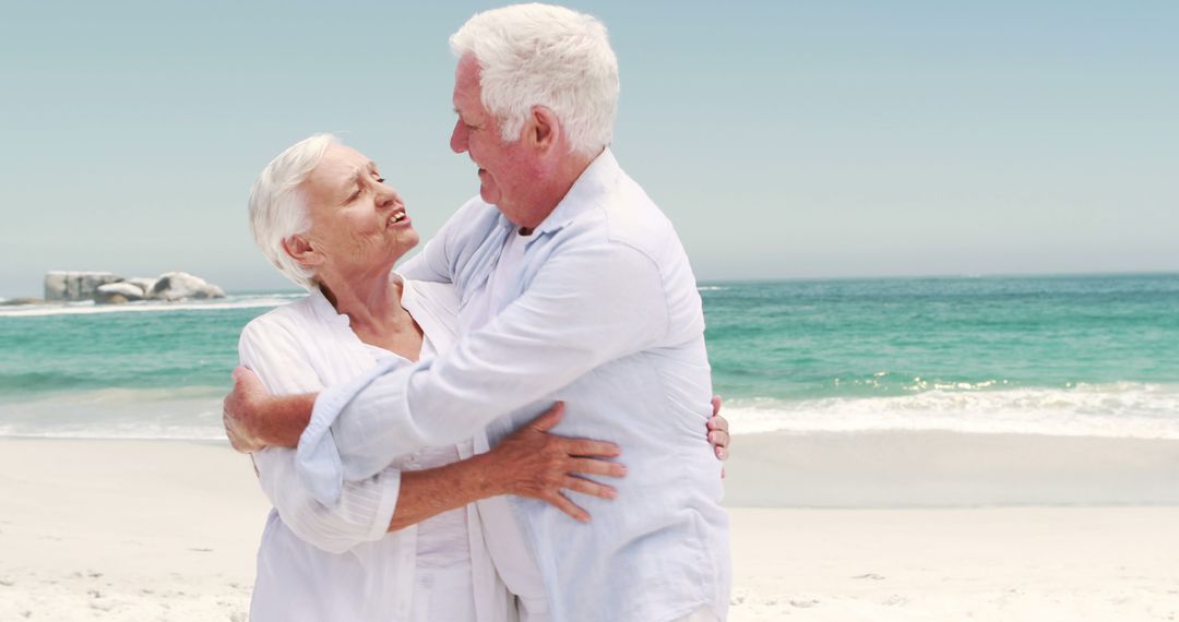 Senior Couple Embracing on Beach During Leisurely Walk - Free Images, Stock Photos and Pictures on Pikwizard.com