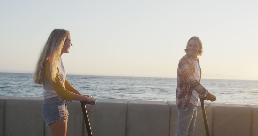 Young Couple Riding Electric Scooters by the Sea During Sunset - Free Images, Stock Photos and Pictures on Pikwizard.com