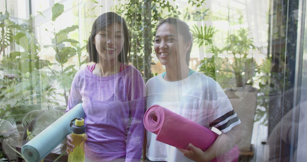 Two Women Holding Yoga Mats and Smiling in Indoor Garden - Free Images, Stock Photos and Pictures on Pikwizard.com