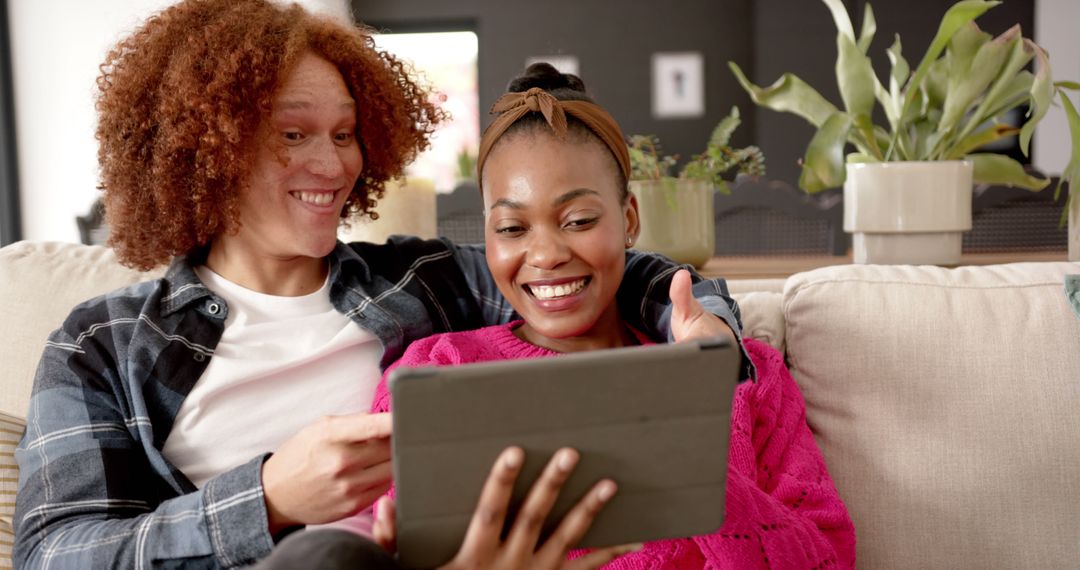 Happy Couple Relaxing on Couch Together Enjoying Tablet