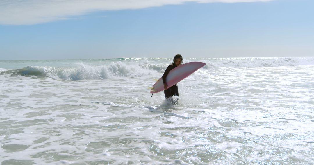 Surfer with Pink Board Ventures into Ocean Waves - Free Images, Stock Photos and Pictures on Pikwizard.com