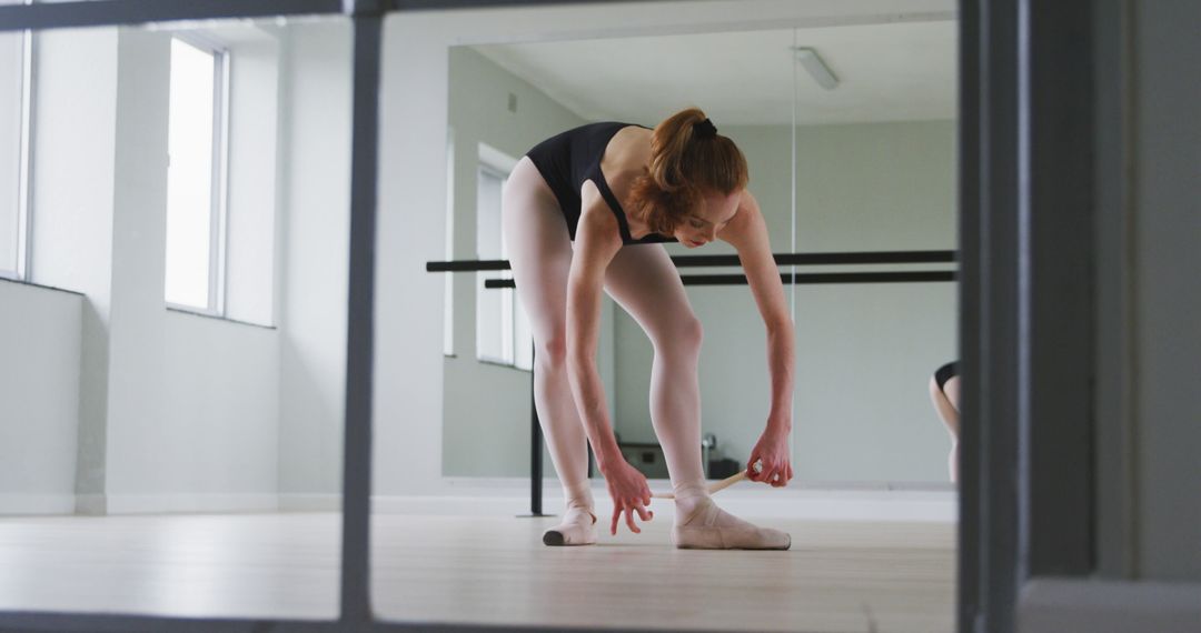 Ballet dancer stretching in studio before practice - Free Images, Stock Photos and Pictures on Pikwizard.com