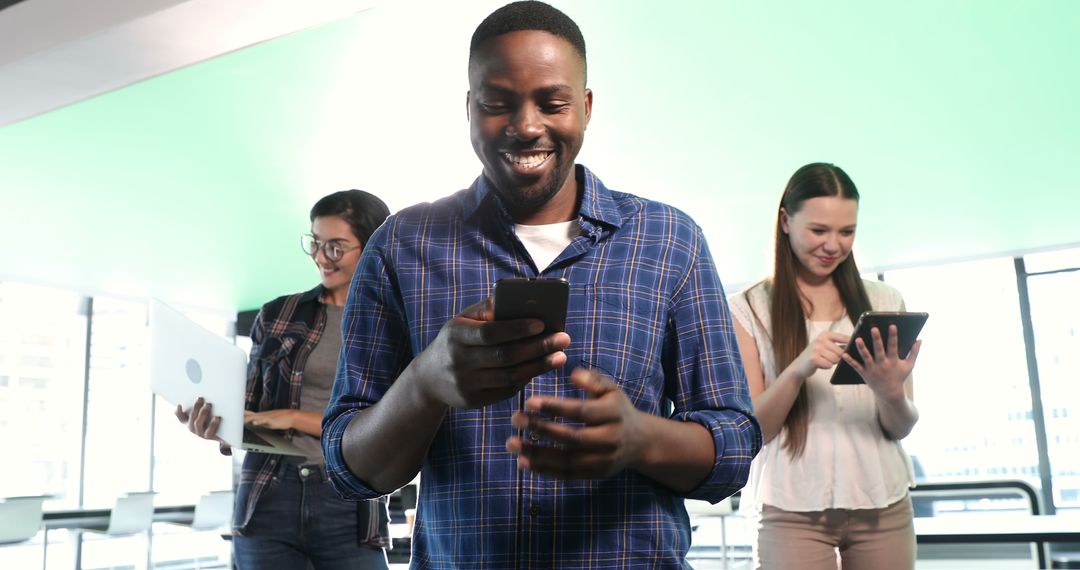 Smiling Man Using Smartphone in Tech-Savvy Office