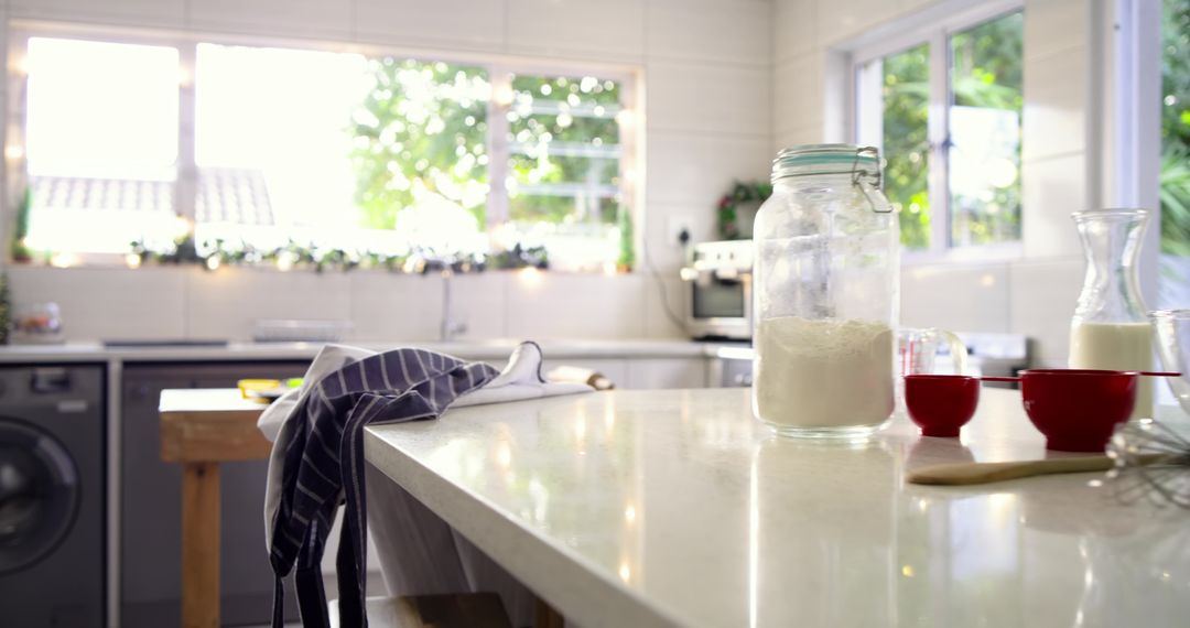 Sunlit kitchen island with flour jar and red measuring cups for home baking