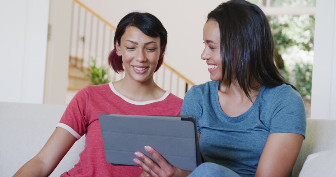 Smiling Women Using Tablet on Couch in Living Room - Free Images, Stock Photos and Pictures on Pikwizard.com