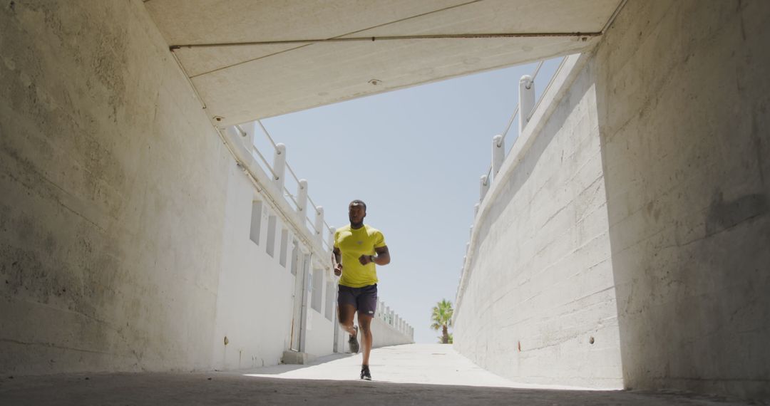 Man jogging through concrete underpass on bright sunny day - Free Images, Stock Photos and Pictures on Pikwizard.com