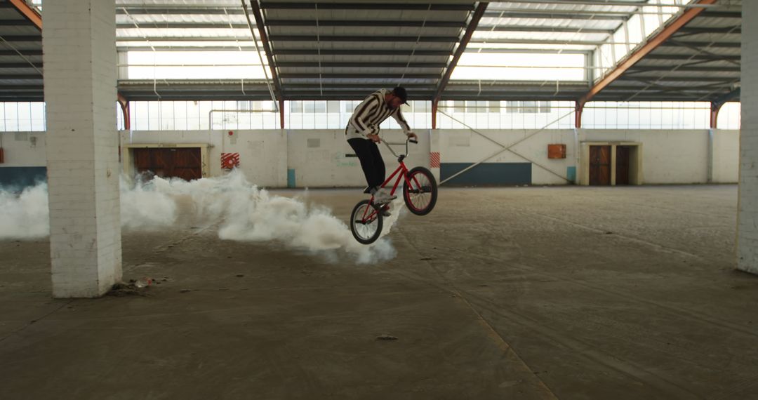 BMX cyclist performing tricks in abandoned warehouse - Free Images, Stock Photos and Pictures on Pikwizard.com