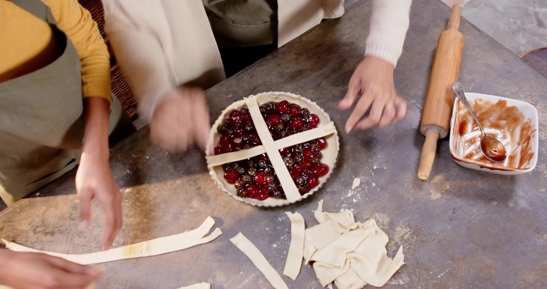 Assembling cherry tart with pastry lattice on flour-dusted counter, hands placing strips