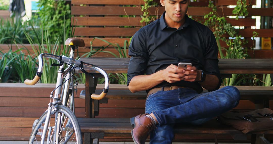 Young Man Sitting on Bench Using Smartphone Near Bicycle Outdoors - Free Images, Stock Photos and Pictures on Pikwizard.com