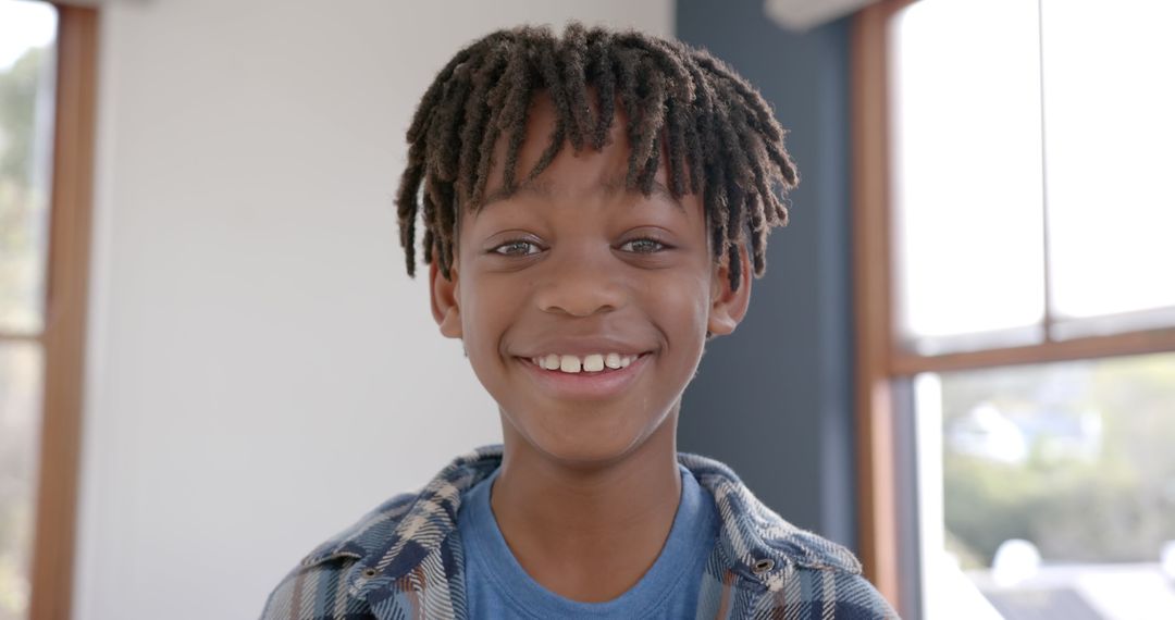 Smiling Boy with Braided Hair Standing by Window
