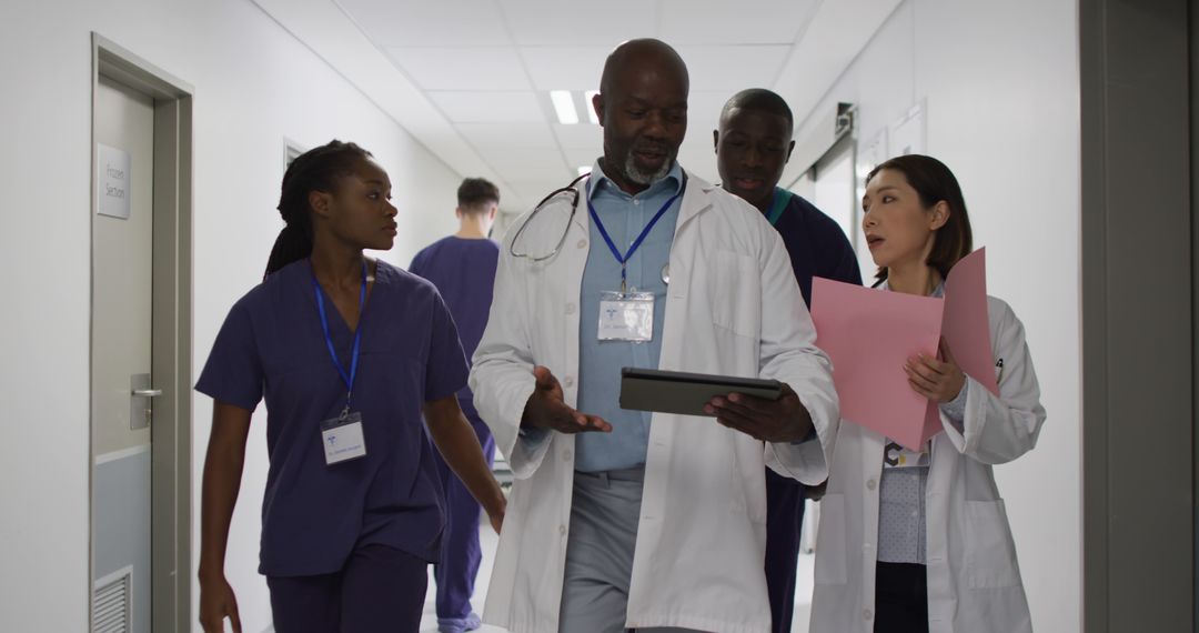 Diverse Medical Team Discussing Patient Files in Hospital Corridor - Free Images, Stock Photos and Pictures on Pikwizard.com