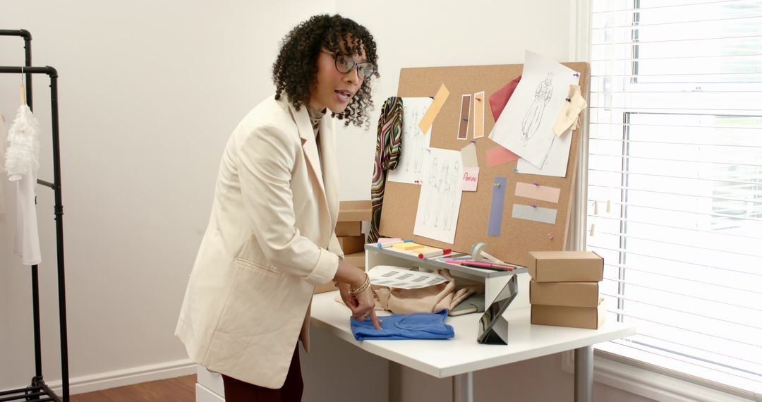 Fashion Designer Arranging Fabric and Sketches at Bright Studio Worktable