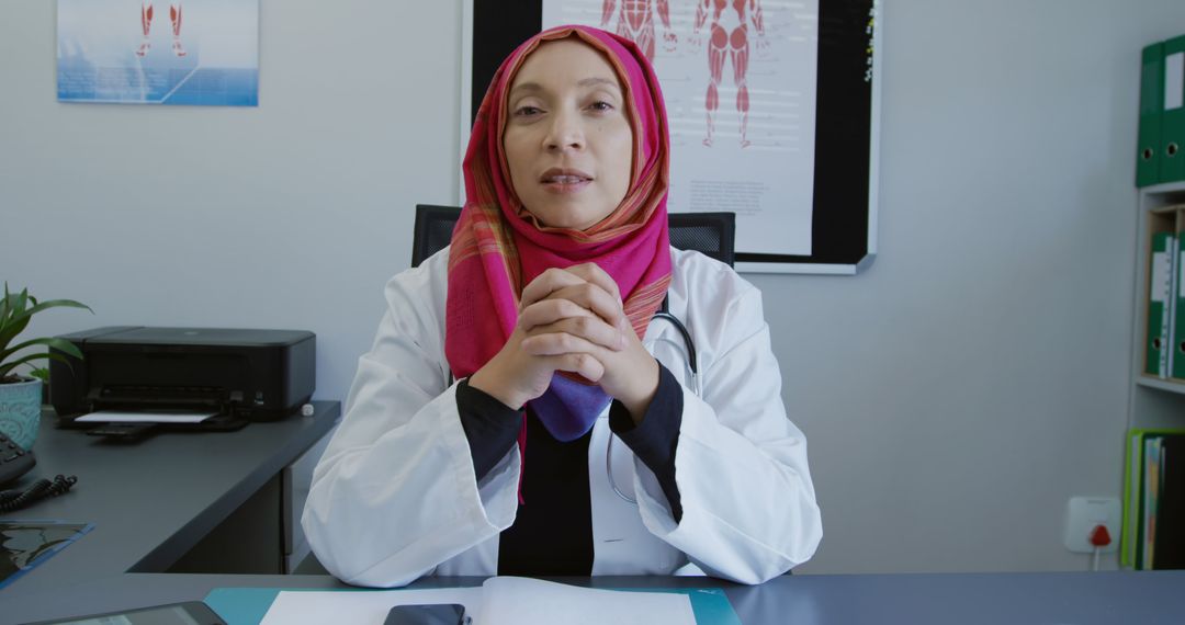 Confident Female Doctor in Hijab Explaining Medical Concepts at Office Desk - Free Images, Stock Photos and Pictures on Pikwizard.com