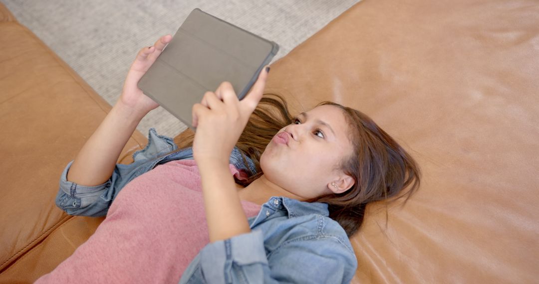 Teen Girl Engaged with Tablet on Sofa Relaxing at Home