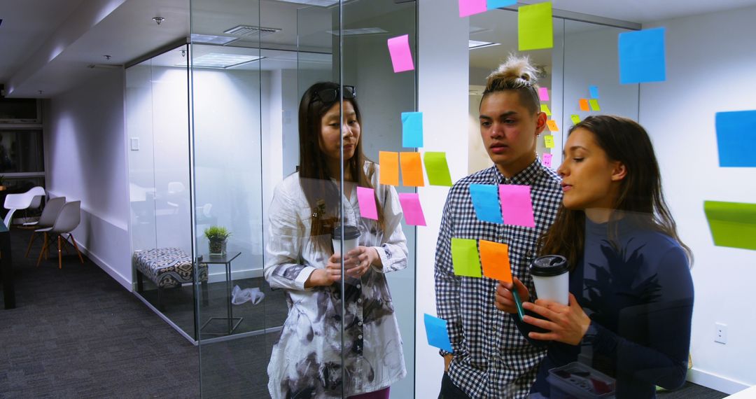 Colleagues Reviewing Ideas on Bright Sticky Notes in Office