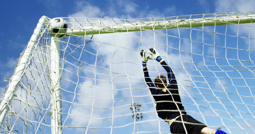 Goalkeeper Trying to Save Soccer Ball in Net Under Blue Sky - Free Images, Stock Photos and Pictures on Pikwizard.com