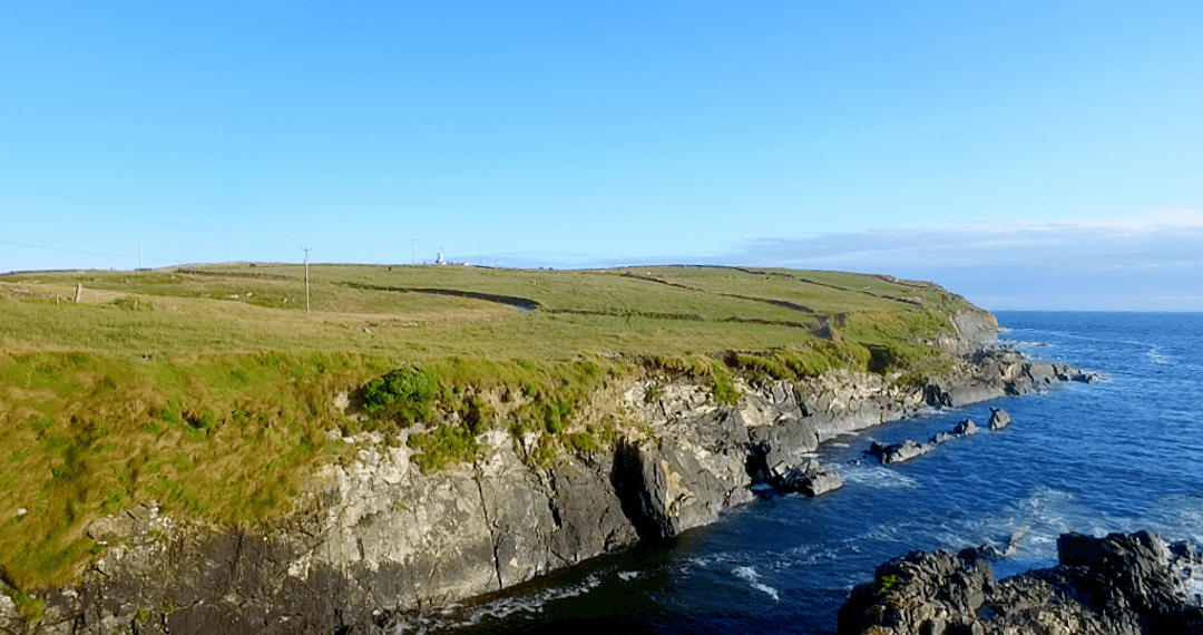 Transparent Blue Sky Over Coastal Grasslands and Rocky Cliffs