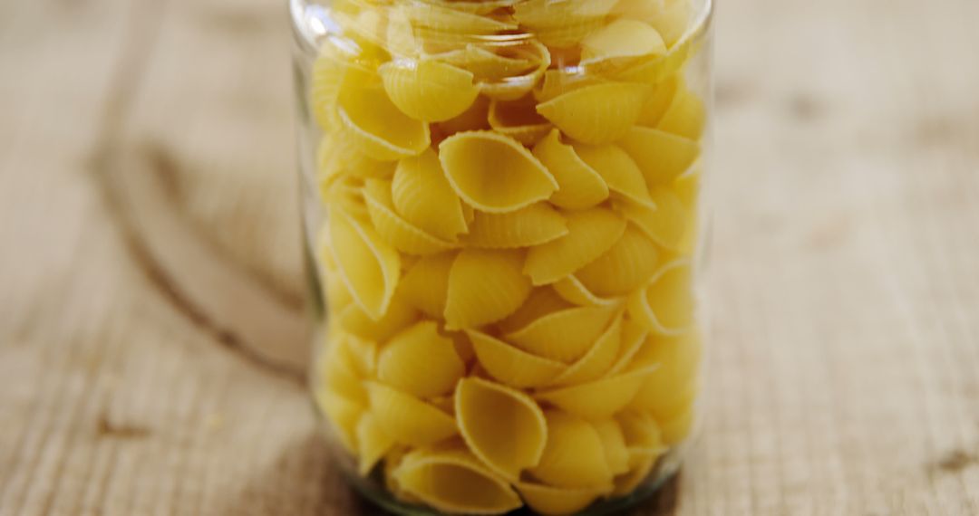 Close-Up of Uncooked Pasta Shells in Glass Jar on Wooden Table - Free Images, Stock Photos and Pictures on Pikwizard.com