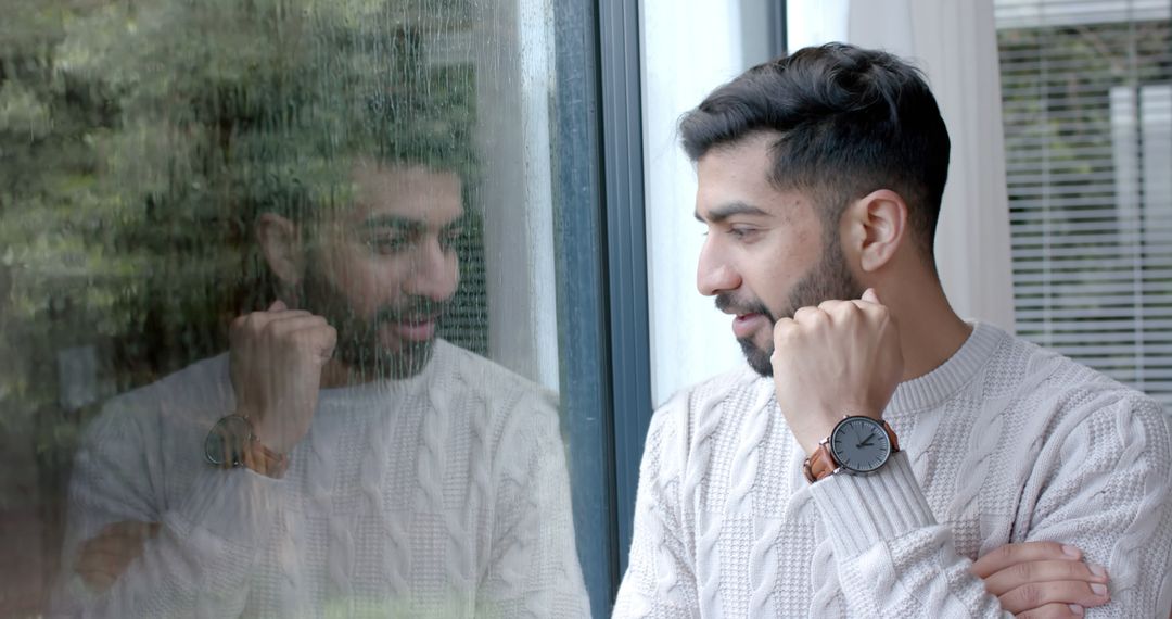 Man Wearing Sweater and Watch Looking Out Window in Thoughtful Pose - Free Images, Stock Photos and Pictures on Pikwizard.com