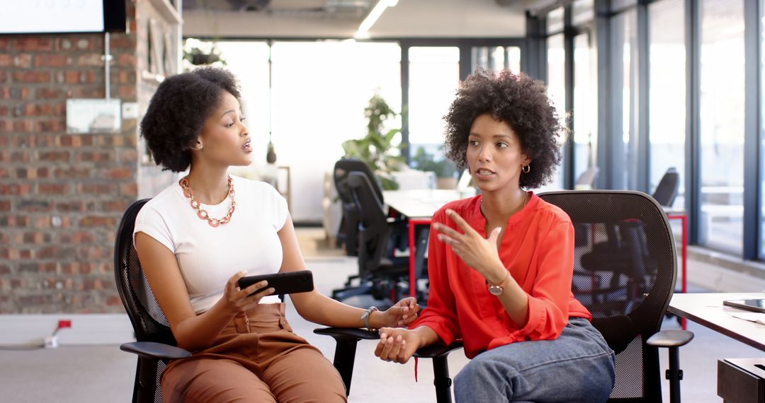 Two Businesswomen Collaborating in Modern Office with Tablet