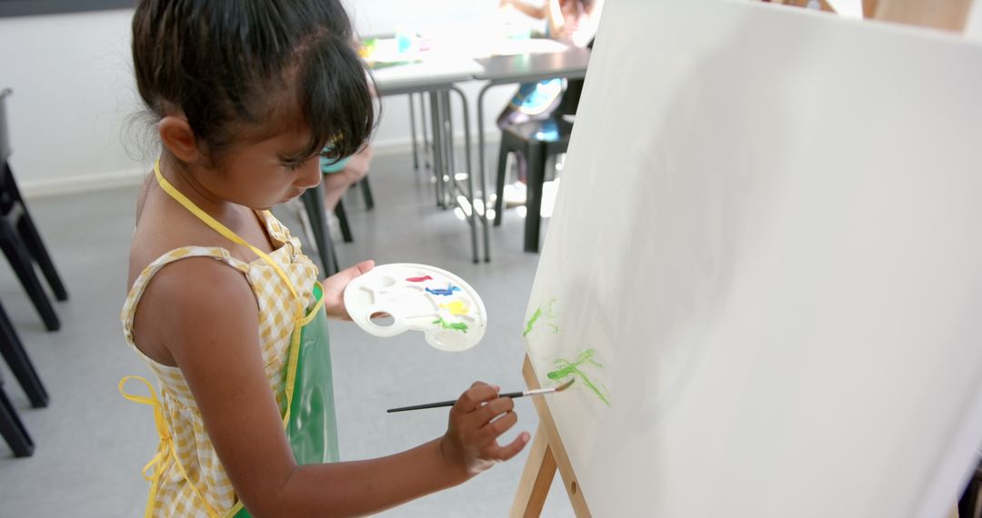 Biracial Girl Expressing Creativity Through Painting in Classroom