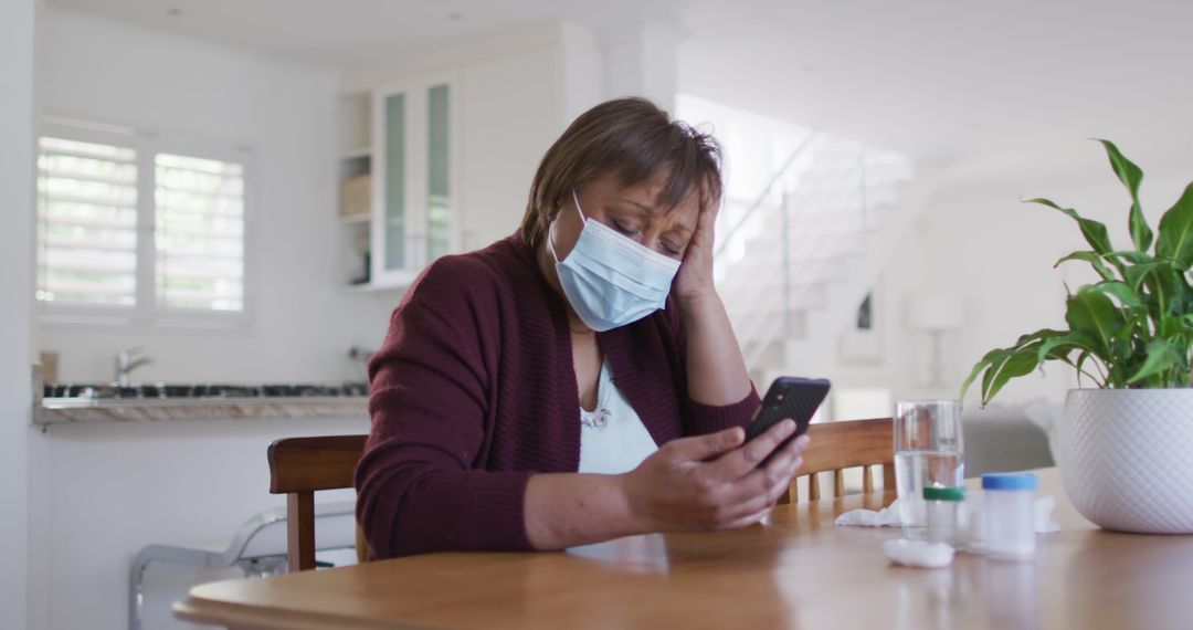 Senior Woman in Face Mask Looking at Smartphone Feeling Unwell - Free Images, Stock Photos and Pictures on Pikwizard.com