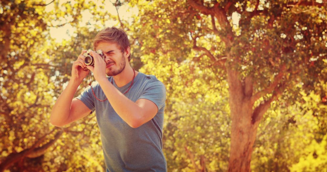 A young Caucasian man is capturing a moment with a vintage camera outdoors, with copy space - Free Images, Stock Photos and Pictures on Pikwizard.com