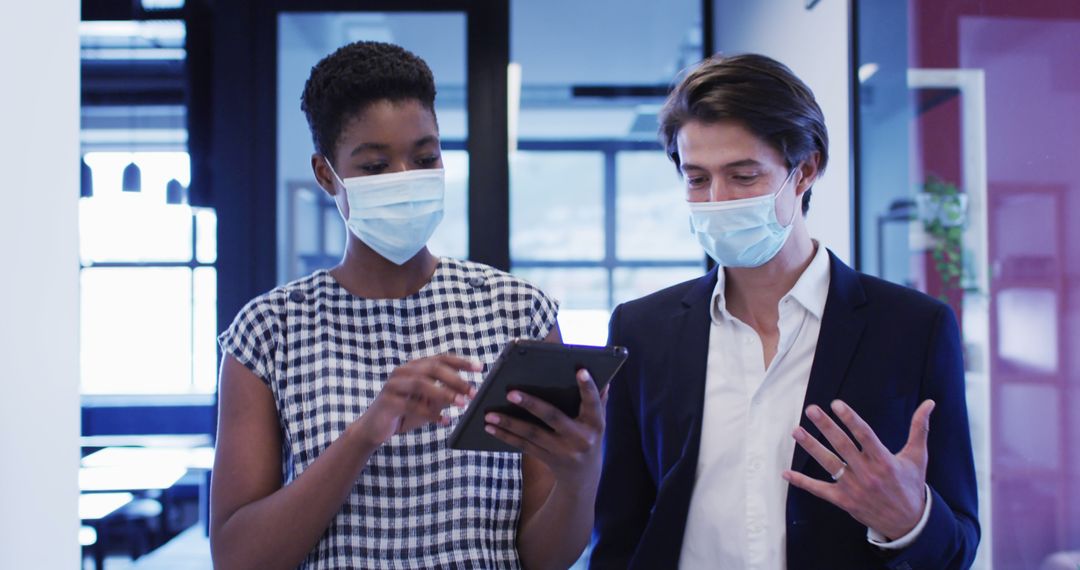 Business Professionals Discussing with Tablet While Wearing Masks in Office