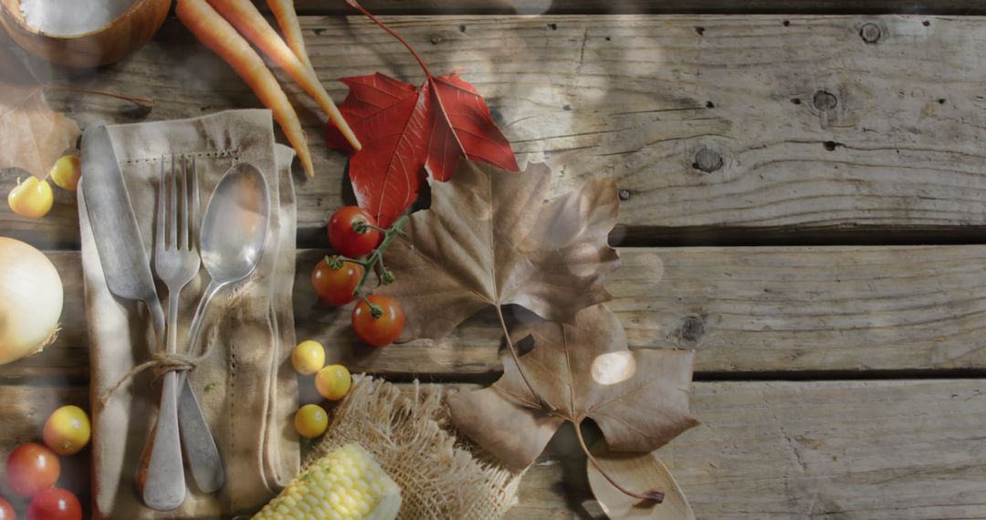 Autumn Feast Preparation with Cutlery and Leaves on Rustic Wood