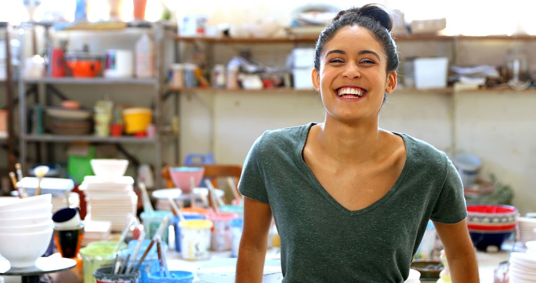 Smiling Young Woman in Pottery Studio Surrounded by Ceramics - Free Images, Stock Photos and Pictures on Pikwizard.com