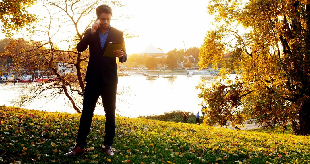 Businessman with Tablet Talking on Phone Outdoor in Autumn Park - Free Images, Stock Photos and Pictures on Pikwizard.com